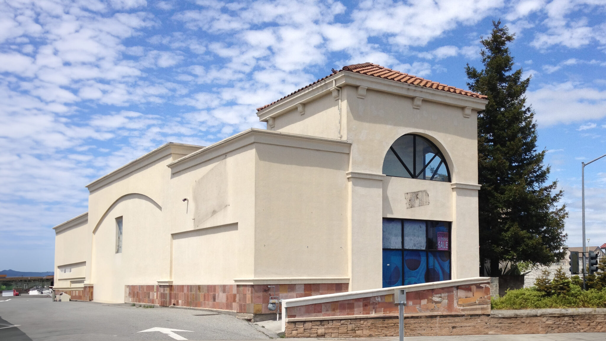 daytime photograph of a former Blockbuster Video store with removed store signs a blue sky with scattered clouds